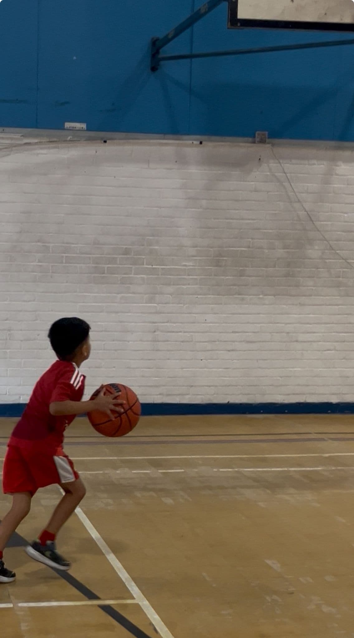 A young member lining up a shot during an indoor basketball session