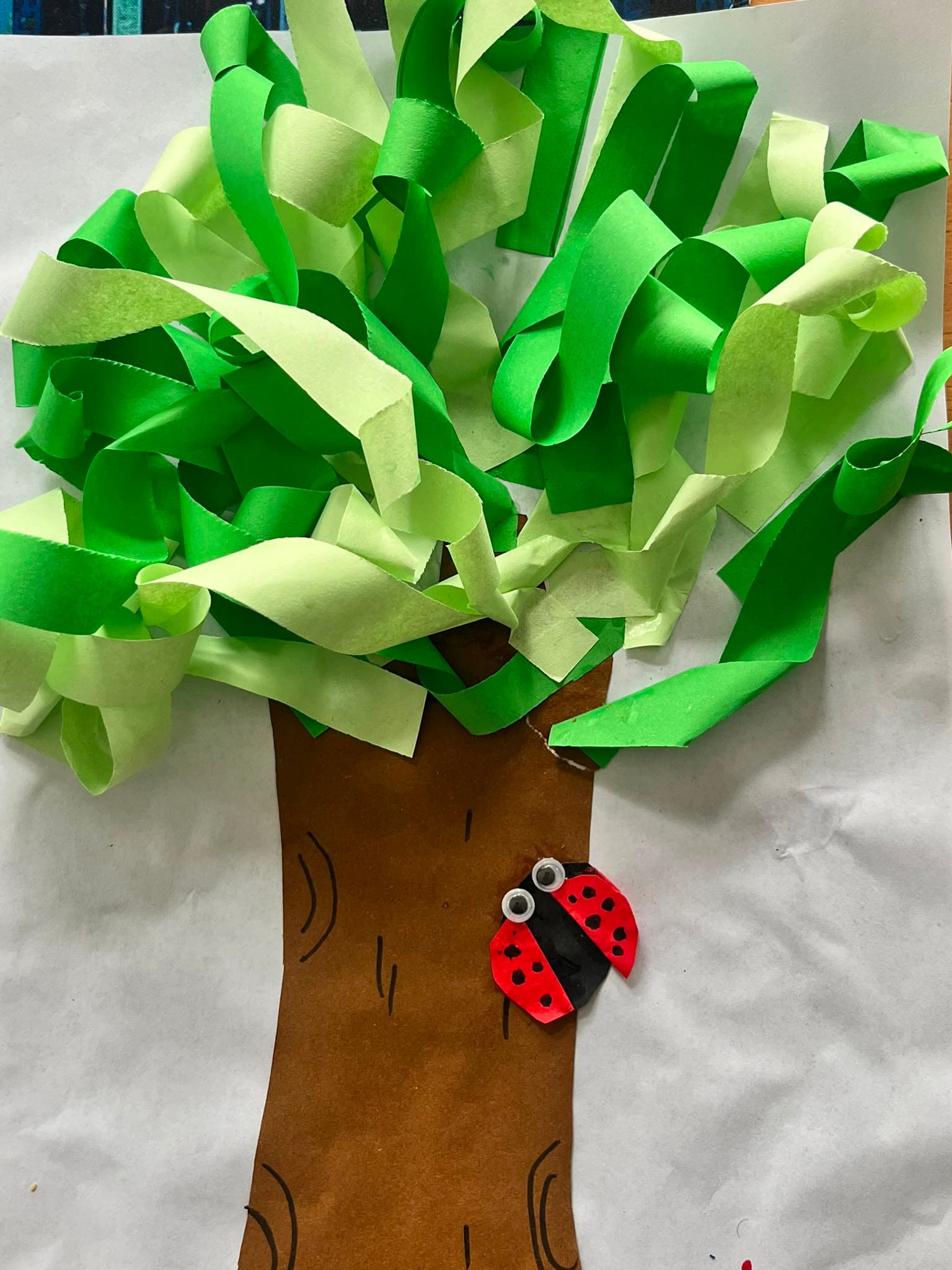 A paper collage tree with a ladybird, made by a young member at a Youth Active Arts & Craft session